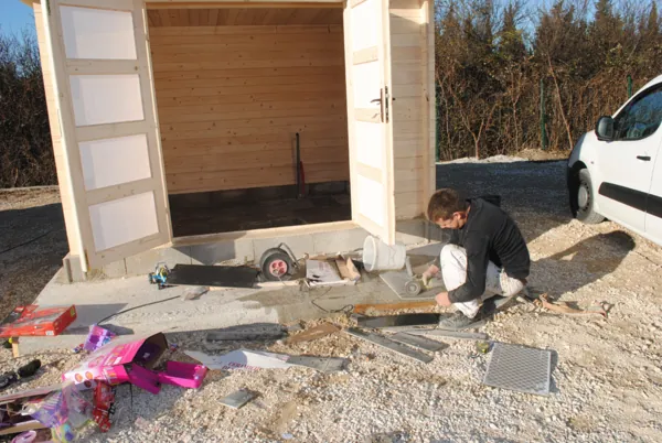 Pose de dalles devant la porte d’un abri de jardin en bois