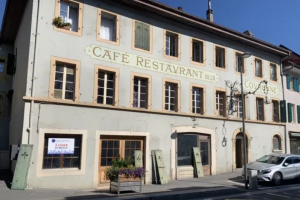 Façade d’un café-restaurant ancien aux volets verts repeints