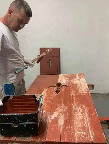 Volet bois rouge en cours de décapage sur l’établi