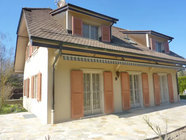 Maison repeinte aux volets rouges vue depuis le jardin