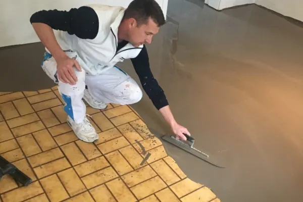 Application à la lisseuse d’un enduit de reprise sur un ancien carrelage jaune