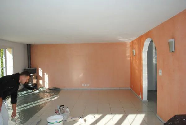Séjour dont un mur a été peint en corail par Stump Rénovation