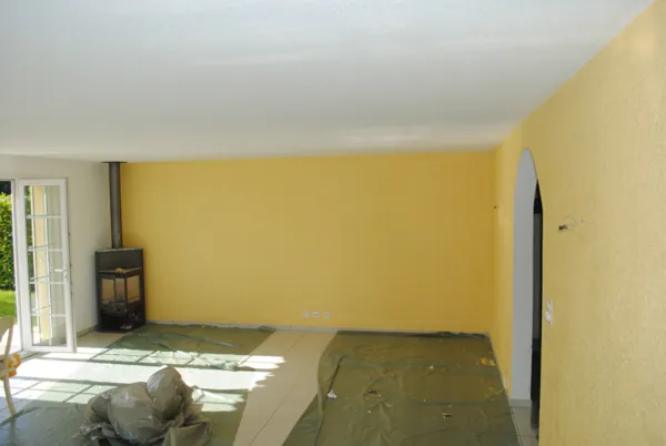 Pièce à vivre avec un mur jaune vif et un poêle, protections au sol