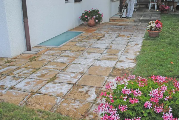 Terrasse en dalles de pierre bordée de fleurs, réalisée par Stump Rénovation