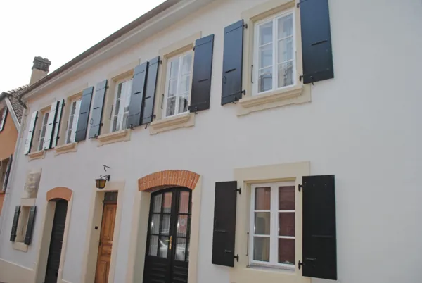 Volets noirs sur une façade blanche, encadrements peints