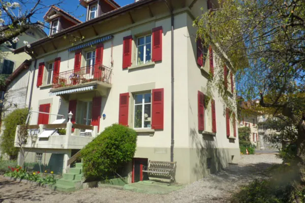 Chalet aux volets rouges repeints, façade claire