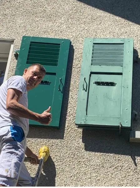 Deux volets verts restaurés posés au sol après séchage
